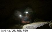 Two young hikers explorers stuck in the narrow hole in dark cave. Стоковое видео, видеограф Константин Шишкин / Фотобанк Лори