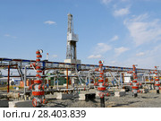 Россия, Тюменская область, Уватский район; Усть-Тегусское нефтяное месторождение; Кустовая площадка №1, ряд задвижек с измерительными приборами на фоне буровой вышки. Стоковое фото, фотограф Александр Циликин / Фотобанк Лори