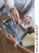 Confident practitioner consulting woman in hospital. Explaining results of chest x-ray scan. Стоковое фото, агентство Ingram Publishing / Фотобанк Лори