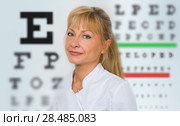 Female optician standing in front of eyesight test at hospital. Стоковое фото, фотограф Kirill Kedrinskiy / Ingram Publishing / Фотобанк Лори