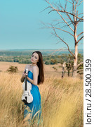 Young beautiful woman in dark cyan dress holds white fiddle. Стоковое фото, фотограф Olena Mykhaylova / Ingram Publishing / Фотобанк Лори