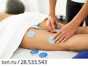 Physiotherapist applying electro stimulation in physical therapy to a young woman leg. . Стоковое фото, фотограф Javier Sánchez Mingorance / Ingram Publishing / Фотобанк Лори