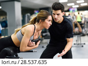 Personal trainer helping young woman lift weights while working out in a gym. Стоковое фото, фотограф Javier Sánchez Mingorance / Ingram Publishing / Фотобанк Лори