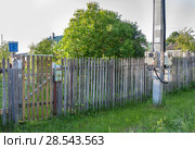 Деревенская улица, старый забор дома номер 13. Домовые электросчетчики в деревне висят на уличном бетонном столбе. Стоковое фото, фотограф Наталья Николаева / Фотобанк Лори