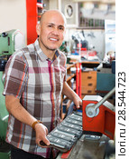 Smiling senior man doing vehicle numbers on machine. Стоковое фото, фотограф Яков Филимонов / Фотобанк Лори