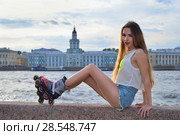 Красивая девушка в роликовых коньках стоит на набережной реки Нева на фоне Дворцового моста в Санкт-Петербурге (2018 год). Редакционное фото, фотограф Максим Мицун / Фотобанк Лори