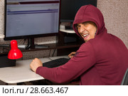 Интернет тролль у компьютера. Неприятный молодой человек пишет гадости на форуме и радуется. Стоковое фото, фотограф Лариса Капусткина / Фотобанк Лори