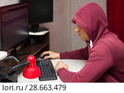 Интернет тролль у компьютера. Агрессивный мужчина в капюшоне сидит в социальных сетях. Стоковое фото, фотограф Лариса Капусткина / Фотобанк Лори