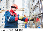 Concrete reinforcement. Builder knitting metal rods with wire. Стоковое фото, фотограф Дмитрий Калиновский / Фотобанк Лори