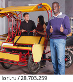 Smiling African-American pedicab driver standing near rickshaw cycle. Стоковое фото, фотограф Яков Филимонов / Фотобанк Лори