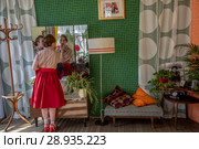 Советская девушка одевается на танцы в своей квартире. Реконструкция времен хрущевской оттепели в рамках фестиваля "Времена и эпохи" в городе Москве, Россия (2018 год). Редакционное фото, фотограф Николай Винокуров / Фотобанк Лори