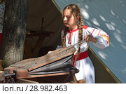 Москва, девушка в народном платье раздувает меха старинной кузнечной печи на Чистопрудном бульваре в период проведения фестиваля "Времена и эпохи" (2018 год). Редакционное фото, фотограф Овчинникова Ирина / Фотобанк Лори