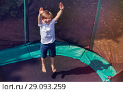 Excited boy bouncing on the trampoline outdoors. Стоковое фото, фотограф Сергей Новиков / Фотобанк Лори