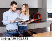 Young beautiful couple standing with book in modern kitchen inte. Стоковое фото, фотограф Яков Филимонов / Фотобанк Лори