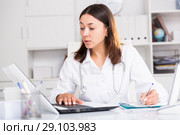 Practicioner girl in medical uniform is working with documents and laptop. Стоковое фото, фотограф Яков Филимонов / Фотобанк Лори