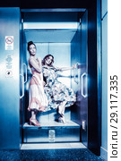 Dark color toned picture of two fashionable sexy girl in the elevator. Стоковое фото, фотограф Игорь Бородин / Фотобанк Лори