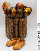 Russian souvenir spoon bast shoes handmade from wood and birch bark are in a wooden vase in the composition painted with bright colors. Стоковое фото, фотограф Марина Бурова / Фотобанк Лори
