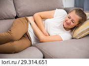 Girl is lying unhappy because she has a stomach ache. Стоковое фото, фотограф Яков Филимонов / Фотобанк Лори