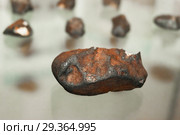 Fragment of a meteorite on a glass showcase close up, against the background of other blurry fragments. Стоковое фото, фотограф Евгений Харитонов / Фотобанк Лори