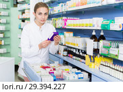 Woman pharmacist is holding medicines near shelves in apothecary. Стоковое фото, фотограф Яков Филимонов / Фотобанк Лори