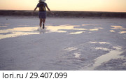 girl in green sandals splash jump through the puddles of salt lake at sunset time. Стоковое видео, видеограф Ирина Мойсеева / Фотобанк Лори