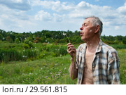 Пожилой мужчина с одуванчиком на летнем лугу. Стоковое фото, фотограф Короленко Елена / Фотобанк Лори