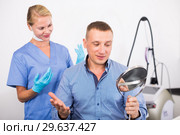 Patient is analysing his skin with using mirror after the procedure. Стоковое фото, фотограф Яков Филимонов / Фотобанк Лори