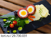 Dish scotch egg with tomatoes, mashed potatoes and greens, traditional Scottish cuisine. Стоковое фото, фотограф Яков Филимонов / Фотобанк Лори