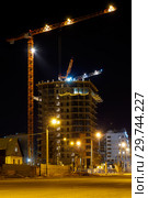 Night shot of construction equipment at building site. Tall cranes and brick buildings under construction at dark summer night. cranes and illumination at night, construction site. Стоковое фото, фотограф Евгений Бобков / Фотобанк Лори