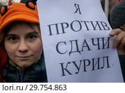 Участница акции против передачи Курильских островов Японии, организованной представителями "Левого фронта" на Суворовской площади города Москвы, держит плакат с надписью "Я против сдачи Курил" (2019 год). Редакционное фото, фотограф Николай Винокуров / Фотобанк Лори