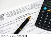 Время платить налоги. Шариковая ручка, калькулятор и незаполненный бланк налоговой декларация на вменённый доход. Стоковое фото, фотограф Игорь Низов / Фотобанк Лори