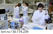 Two young scientists working together in laboratory writing report on results of chemical experiments in notebook. Стоковое видео, видеограф Яков Филимонов / Фотобанк Лори
