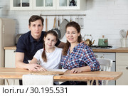 Папа, мама и десятилетняя дочь за столом на кухне, семейный портрет. Стоковое фото, фотограф Кекяляйнен Андрей / Фотобанк Лори