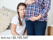 Young girl not happy about new sibling, closing eyes and sobbing along her pregnant mother. Стоковое фото, фотограф Кекяляйнен Андрей / Фотобанк Лори