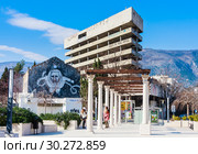 Graffiti on the building on Spanish Square, Mostar, Bosnia. Abandoned bank building (sniper tower during war) on background (2018 год). Редакционное фото, фотограф Николай Коржов / Фотобанк Лори