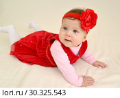 Шестимесячная девочка с красным цветком на голове лежит на животе. Стоковое фото, фотограф Ирина Борсученко / Фотобанк Лори