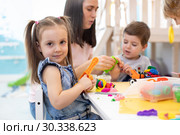 Teacher teaches kids modeling clay in playroom at kindergarten. Стоковое фото, фотограф Оксана Кузьмина / Фотобанк Лори