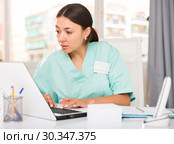 Practicioner girl in medical uniform is working at laptop. Стоковое фото, фотограф Яков Филимонов / Фотобанк Лори