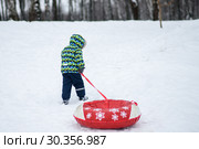 Маленький мальчик с тюбингом поднимается в горку. Стоковое фото, фотограф Игорь Низов / Фотобанк Лори