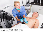 Woman doctor is doing vacuum massage procedure on belly of adult client. Стоковое фото, фотограф Яков Филимонов / Фотобанк Лори