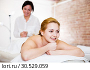Masseuse massaging back zone of young smiling woman. Стоковое фото, фотограф Яков Филимонов / Фотобанк Лори
