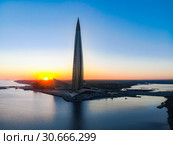 Saint Petersburg, RUSSIA - April 16 2019: Public, business complex Lakhta center, Skyscraper Gazprom headquarters. Gulf of Finland. Clear blue sky on sunset. Reflection in water. Top view aerial drone. Редакционное фото, фотограф Алексей Ширманов / Фотобанк Лори