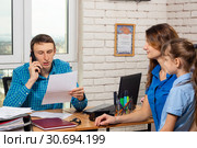 Офисный специалист звонит по телефону, на приеме мама с ребенком. Стоковое фото, фотограф Иванов Алексей / Фотобанк Лори