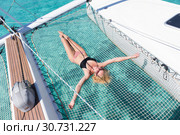 Woman relaxing on a summer sailing cruise,lying in hammock of luxury catamaran near picture perfect white sandy beach on Spargi island in Maddalena Archipelago, Sardinia, Italy. Стоковое фото, фотограф Matej Kastelic / Фотобанк Лори