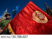 Мужчина держржит красное знамя с вышитым гербом Союза Советских Социалистических Республик на Красной площади в центре города Москвы, Россия (2019 год). Редакционное фото, фотограф Николай Винокуров / Фотобанк Лори
