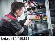 Electrician works with pliers in switchbox. current breaker installation. Стоковое фото, фотограф Дмитрий Калиновский / Фотобанк Лори