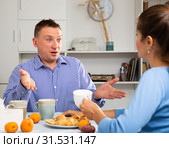 Upset man and frustrated woman arguing at home kitchen. Focus on woman. Стоковое фото, фотограф Яков Филимонов / Фотобанк Лори