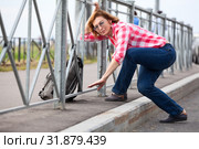 Mature woman get through road fence with her backpack. Urban roadside and pedestrian zone. Стоковое фото, фотограф Кекяляйнен Андрей / Фотобанк Лори