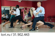 Adult pairs dancing tango movements in modern dance studio. Стоковое фото, фотограф Яков Филимонов / Фотобанк Лори