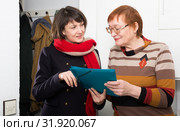 Girl volunteer offers an older woman to read the document. Стоковое фото, фотограф Яков Филимонов / Фотобанк Лори
